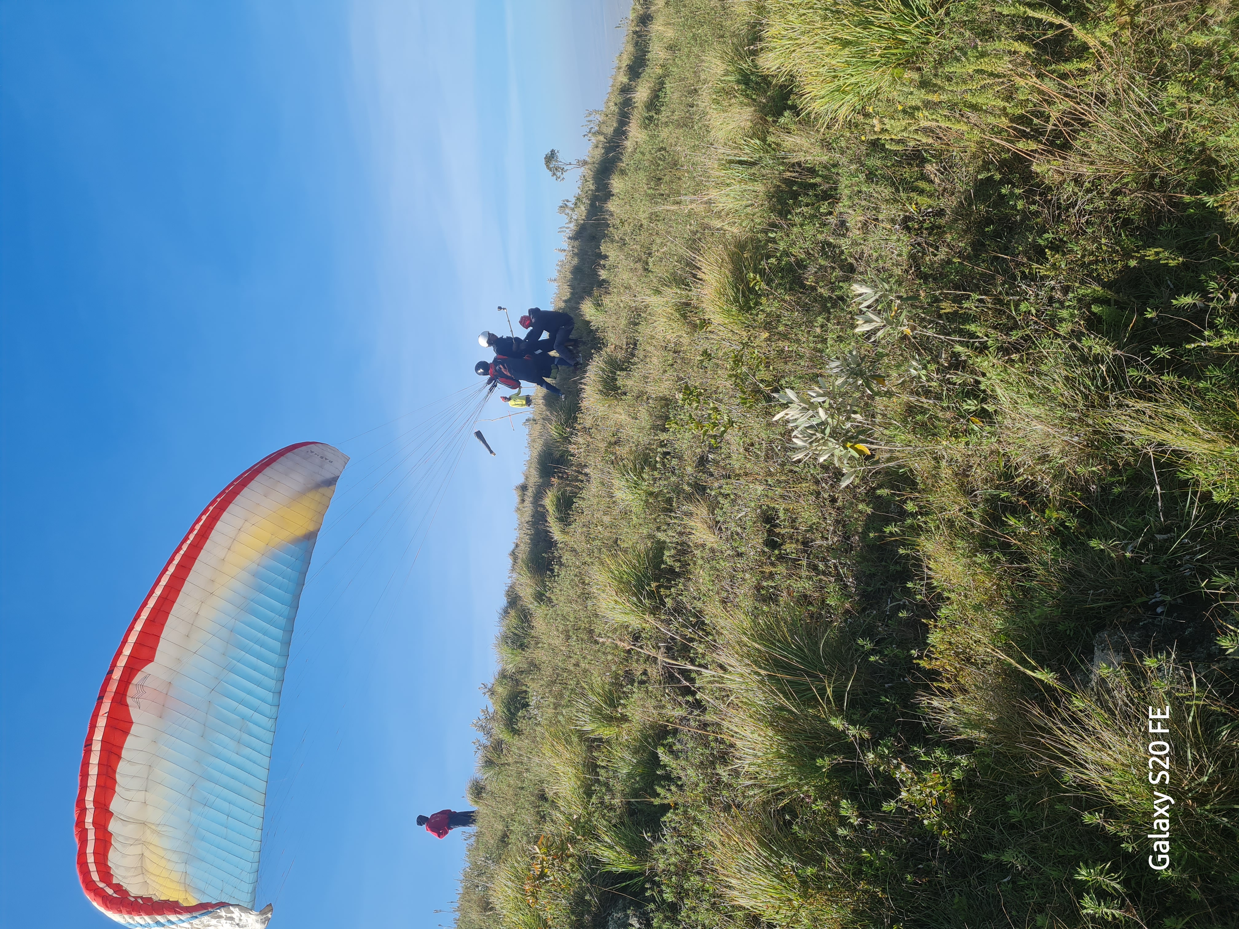 Tandem passenger smiling mid-flight with the valley behind